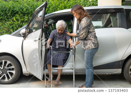 Caregiver help Asian elderly woman disability patient get in her car. Caregiver help Asian elderly woman disability patient get in her car. 137193403