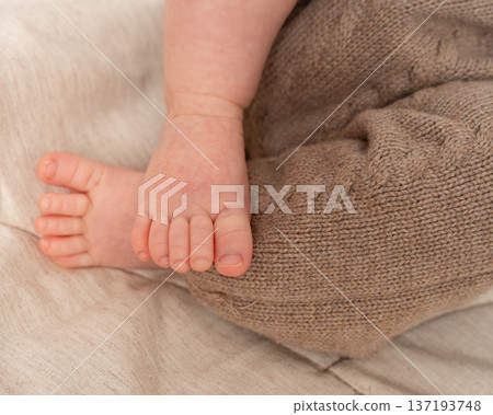 Horizontal close-up of a newborn babys foot resting on a cozy textured blanket. Warm tones, soft natural lighting, and neutral colors make this image perfect for parenting, baby care, and lifestyle Horizontal close-up of a newborn babys foot resting on a cozy textured blanket. Warm tones, soft natural lighting, and neutral colors make this image perfect for parenting, baby care, and lifestyle 137193748