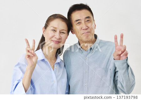 Smiling senior couple making peace signs Smiling senior couple making peace signs 137193798
