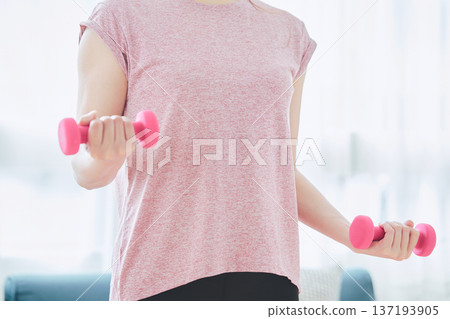Close-up of a woman's arm doing dumbbell exercises at home Close-up of a woman's arm doing dumbbell exercises at home 137193905