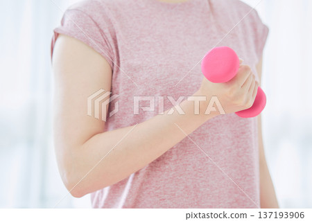 Close-up of a woman's arm doing dumbbell exercises at home Close-up of a woman's arm doing dumbbell exercises at home 137193906