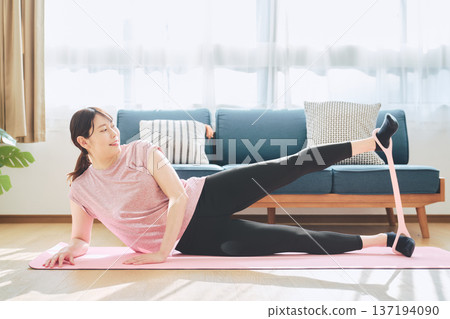 Wellness life of a woman in her 30s exercising at home using training tubes 137194090