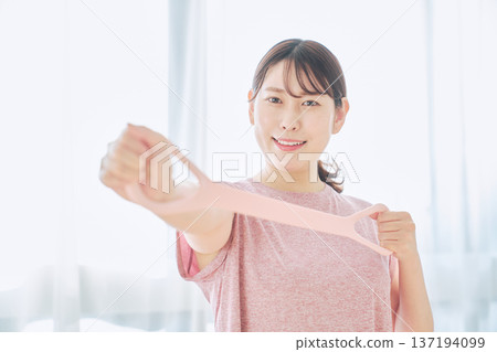 Health-conscious woman doing arm exercises with training tube Health-conscious woman doing arm exercises with training tube 137194099