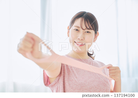 Health-conscious woman doing arm exercises with training tube Health-conscious woman doing arm exercises with training tube 137194100