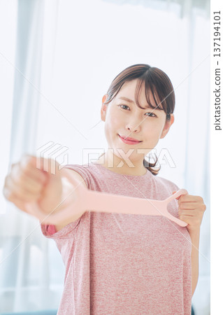 Health-conscious woman doing arm exercises with training tube Health-conscious woman doing arm exercises with training tube 137194101
