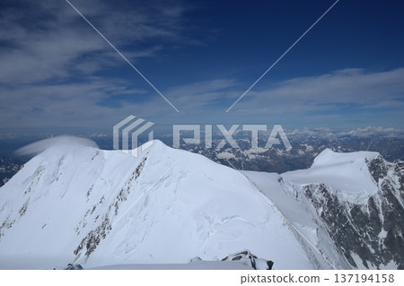A stunning rock formation covered in snow, set against a clear blue sky with fluffy clouds in the background, creating a peaceful and breathtaking mountain landscape. A stunning rock formation covered in snow, set against a clear blue sky with fluffy clouds in the background, creating a peaceful and breathtaking mountain landscape. 137194158