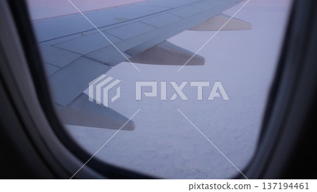 Airplane wing view above clouds during sunset with soft pastel colors Airplane wing view above clouds during sunset with soft pastel colors 137194461