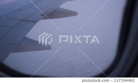 Airplane wing view above cloudy sky during twilight hours Airplane wing view above cloudy sky during twilight hours 137194462