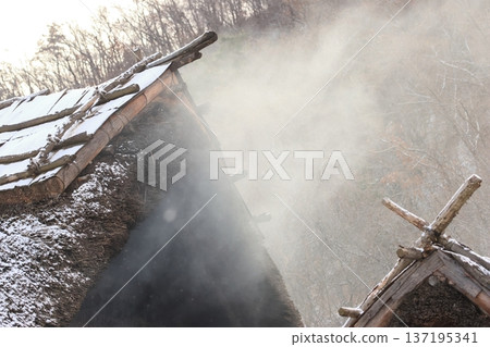 Smoke from a bonfire rising from a restored pit dwelling 137195341