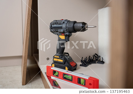 Cordless Drill and Spirit Level on Kitchen Cabinet Shelf 137195463