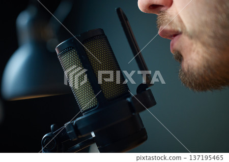 Close up man speaking into studio microphone with pop filter 137195465