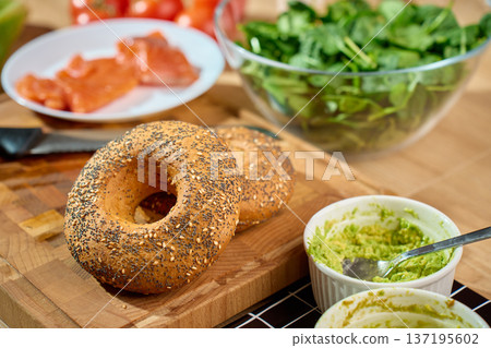 Bagels with mashed avocado spread and salmon ingredients on table Bagels with mashed avocado spread and salmon ingredients on table 137195602