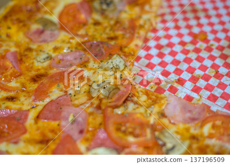 Pepperoni and mushroom pizza close-up on checkered paper 137196509