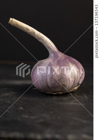 ripe purple garlic is scattered on a black table in the kitchen, garlic spices are on a black slate in the kitchen over cooking ripe purple garlic is scattered on a black table in the kitchen, garlic spices are on a black slate in the kitchen over cooking 137196543