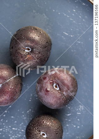 black fresh juicy wet plums on the kitchen table, beautiful clean black plums on the table, the plums are covered with a lot of drops of water black fresh juicy wet plums on the kitchen table, beautiful clean black plums on the table, the plums are covered with a lot of drops of water 137196566