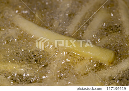 raw French fries in sunflower oil while frying in a frying pan, delicious fast food from frozen French fries in hot oil 137196619
