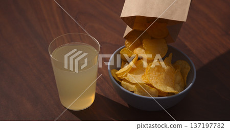 Man hand pour potato chips to blue bowl with ginger beer on background 137197782