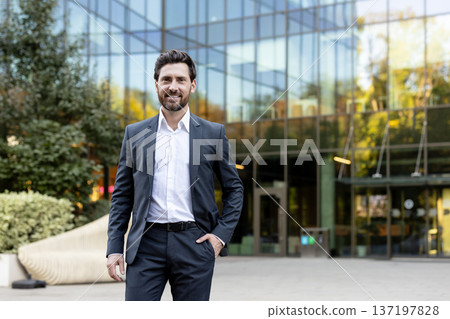 Professional male entrepreneur smiling at camera, standing outdoors in business district, reflecting success, leadership, and professional corporate career goals Professional male entrepreneur smiling at camera, standing outdoors in business district, reflecting success, leadership, and professional corporate career goals 137197828