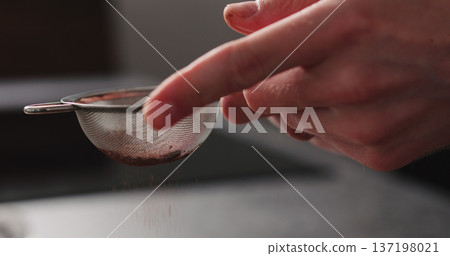 man hand sprinkle cocoa powder from sieve man hand sprinkle cocoa powder from sieve 137198021