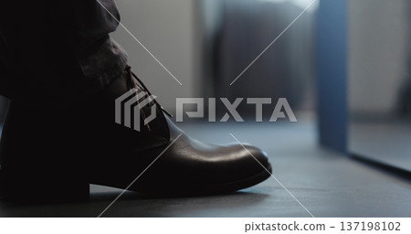 Young man put on his brown leather chukka boots indoor Young man put on his brown leather chukka boots indoor 137198102