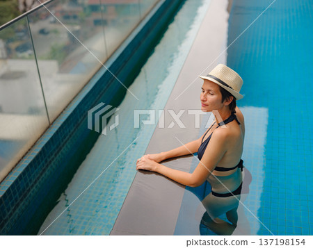 Young woman relaxing by the pool at a Kuala Lumpur hotel Young woman relaxing by the pool at a Kuala Lumpur hotel 137198154