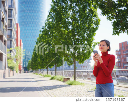 Woman in glasses stands in center of Frankfurt, 137198167