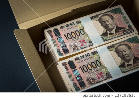 紙箱裡裝著一疊鈔票。畫面陰暗。 紙箱裡裝著一疊鈔票。畫面陰暗。 137198635