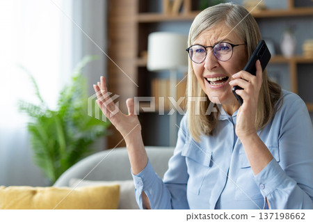 Senior woman with glasses talking on phone indoors looking upset or frustrated. Elderly lady having difficult conversation expressing emotions. Senior woman with glasses talking on phone indoors looking upset or frustrated. Elderly lady having difficult conversation expressing emotions. 137198662