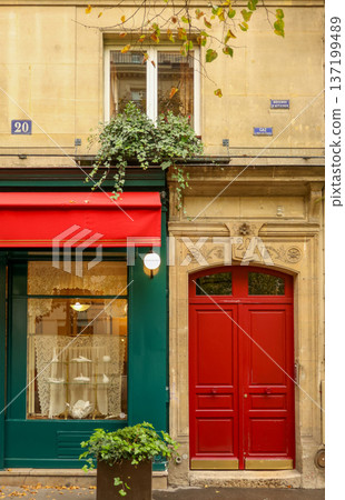 Paris urban architecture featuring vibrant red door, green storefront with awning, and detailed building facade 137199489