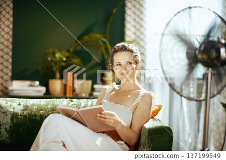 Smiling Woman Enjoying Reading at Home Comfortably Smiling Woman Enjoying Reading at Home Comfortably 137199549