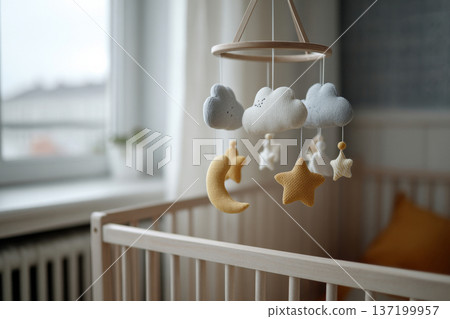 crib mobile gently still above empty crib, soft neutral interior, diffused daylight, calm melancholic atmosphere, horizontal framing 137199957
