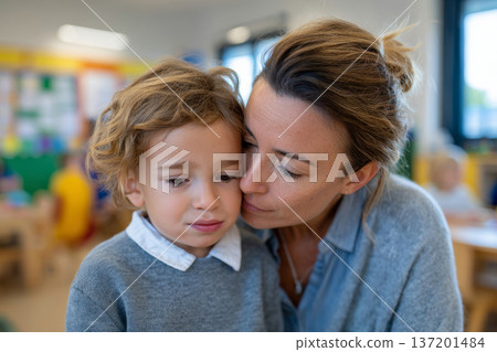 preschool teacher comforting crying child in bright kindergarten classroom, colorful but minimal interior, natural daylight from large windows, candid documentary style, medium shot 137201484