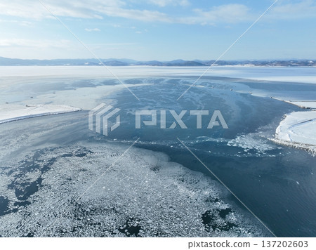 Aerial view of the bay mouth of Lake Saroma and the ice boom in winter, with drifting pieces of ice Aerial view of the bay mouth of Lake Saroma and the ice boom in winter, with drifting pieces of ice 137202603