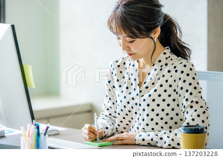 Young woman operating a computer in the office 137203228