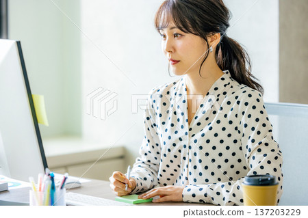 Young woman operating a computer in the office 137203229
