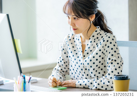 Young woman operating a computer in the office 137203231