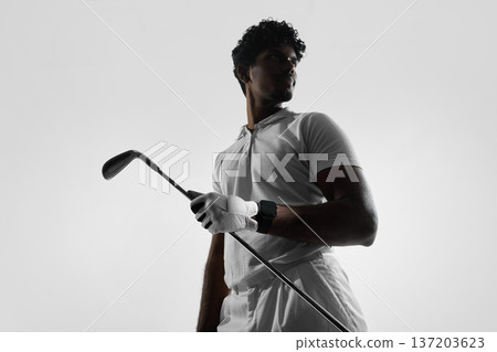 Golfer holding club with smartwatch during practice in studio. Golfer holding club with smartwatch during practice in studio. 137203623