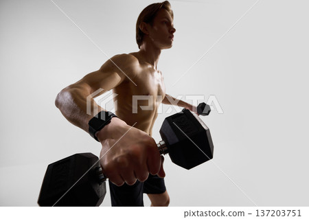 Man performing dumbbell fly exercise wearing smartwatch in studio. Man performing dumbbell fly exercise wearing smartwatch in studio. 137203751