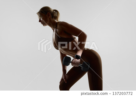 Close up of woman training with dumbbell and smartwatch in studio 137203772