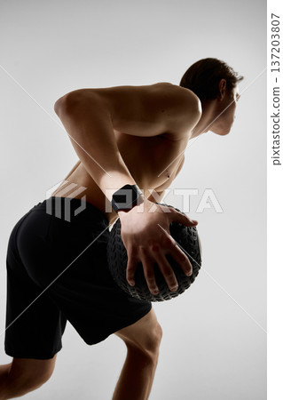 Close up of athlete gripping medicine ball during workout in studio with smartwatch Close up of athlete gripping medicine ball during workout in studio with smartwatch 137203807