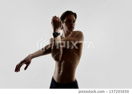 Athletic man stretching with smartwatch in modern studio. 137203830