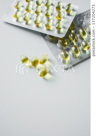 Omega 3 fish oil capsules in blisters on white table close up. Vitamins and supplements, healthcare and medicine. 137204273