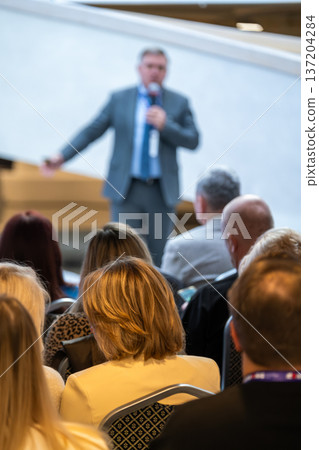 Keynote speaker presents to attentive audience at a modern conference during a corporate event Keynote speaker presents to attentive audience at a modern conference during a corporate event 137204284