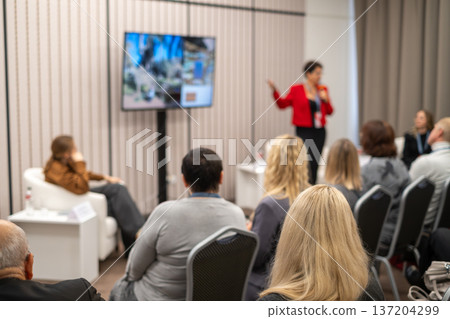 Business conference presentation with speaker and seated audience in small professional meeting room Business conference presentation with speaker and seated audience in small professional meeting room 137204299