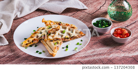 Waffle toasts with ham, cheese and tomato filling on a plate on the table web banner Waffle toasts with ham, cheese and tomato filling on a plate on the table web banner 137204308