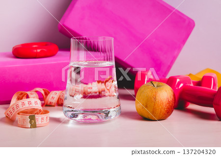Diet and sport concept, glass of water, apple and sports equipment on the table Diet and sport concept, glass of water, apple and sports equipment on the table 137204320
