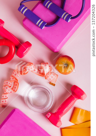 A glass of water and an apple for a diet and sports equipment on the table top and vertical view 137204326