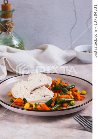 Boiled chicken fillet and mixed vegetables on a plate on the table vertical view Boiled chicken fillet and mixed vegetables on a plate on the table vertical view 137204331