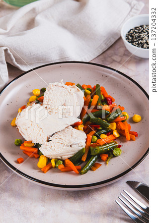 Chicken fillet and mexican mixed vegetables steamed on a plate on the table vertical view 137204332