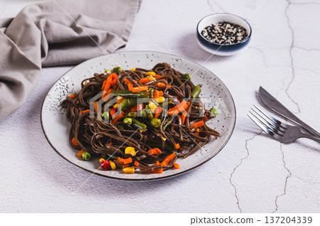Buckwheat soba noodles with vegetables on a plate on the table Buckwheat soba noodles with vegetables on a plate on the table 137204339